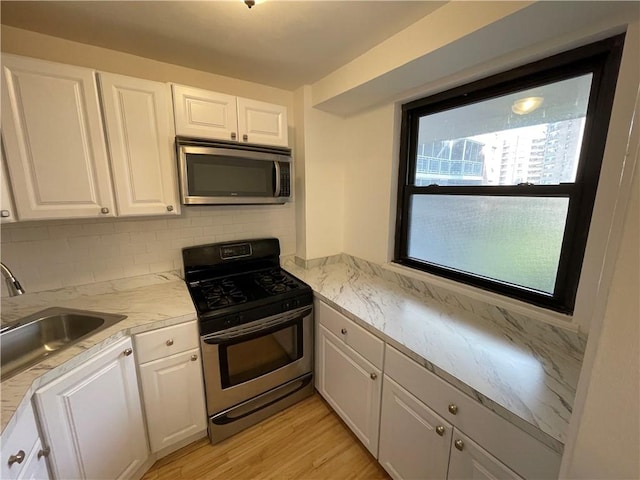 kitchen featuring backsplash, stainless steel appliances, sink, light hardwood / wood-style floors, and white cabinetry