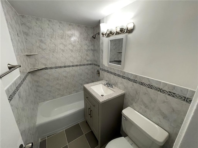 full bathroom with vanity, tile walls, tile patterned flooring, toilet, and tiled shower / bath