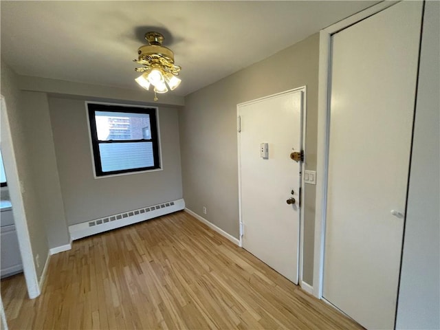 interior space with ceiling fan, light wood-type flooring, and a baseboard heating unit