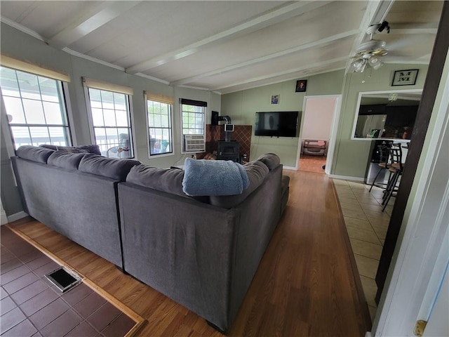 living room with ceiling fan, cooling unit, hardwood / wood-style floors, vaulted ceiling with beams, and a wood stove