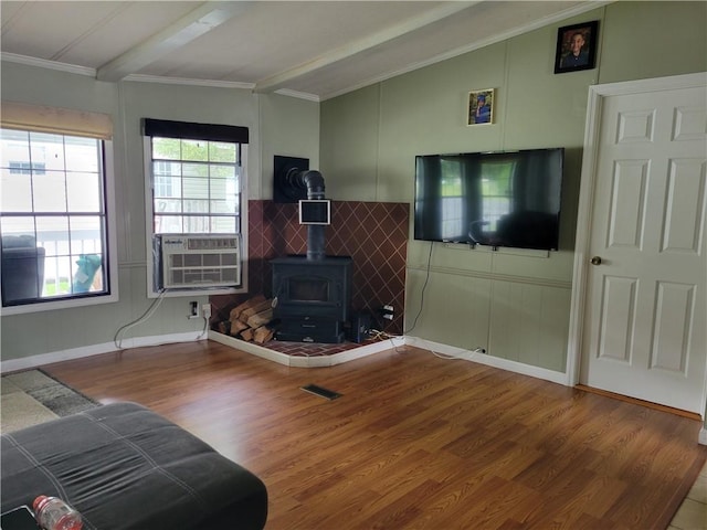 living room with a wood stove, lofted ceiling with beams, crown molding, cooling unit, and wood-type flooring