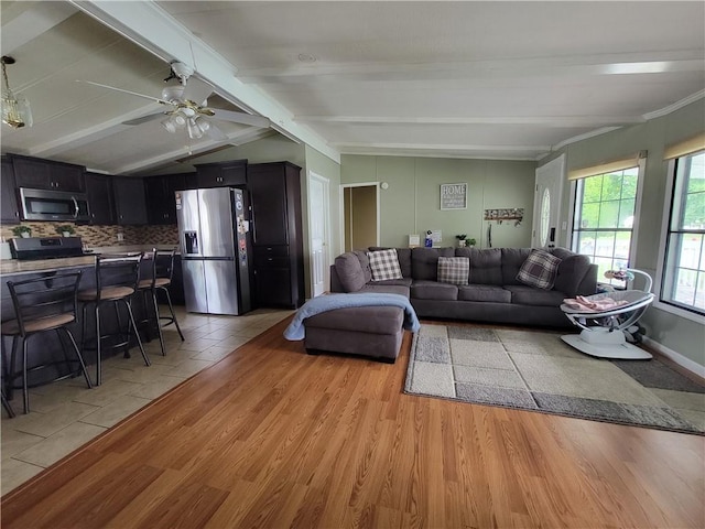 living room featuring vaulted ceiling with beams, ceiling fan, and light wood-type flooring