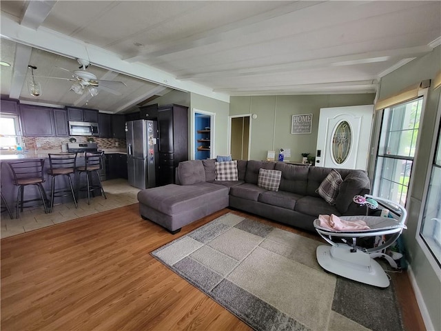 living room with lofted ceiling with beams, light hardwood / wood-style flooring, plenty of natural light, and ceiling fan