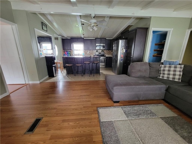 living room with lofted ceiling with beams, light hardwood / wood-style flooring, and ceiling fan