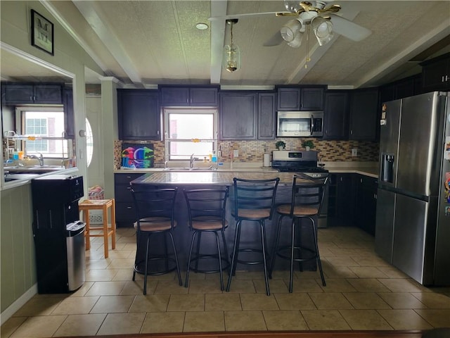 kitchen featuring a wealth of natural light, a kitchen island, a breakfast bar area, and appliances with stainless steel finishes