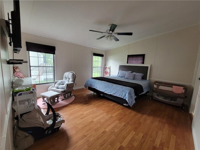 bedroom with ceiling fan, crown molding, wood-type flooring, and vaulted ceiling