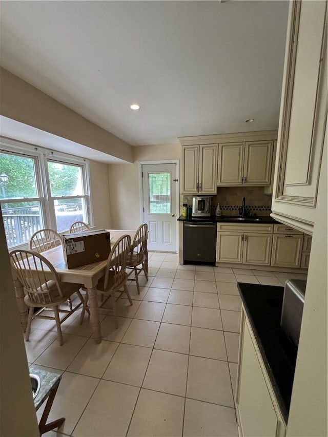 kitchen featuring decorative backsplash, sink, light tile patterned floors, dishwasher, and cream cabinetry