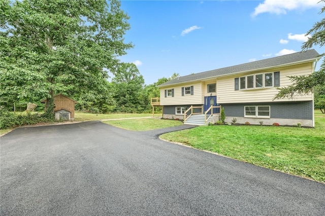 split foyer home featuring a front lawn and a storage shed