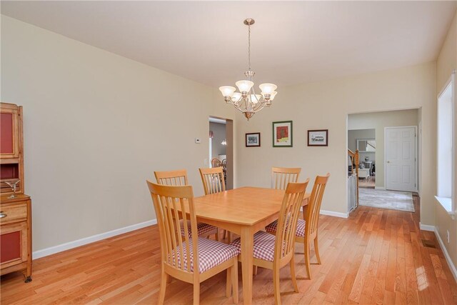 dining area with light wood-type flooring and a chandelier