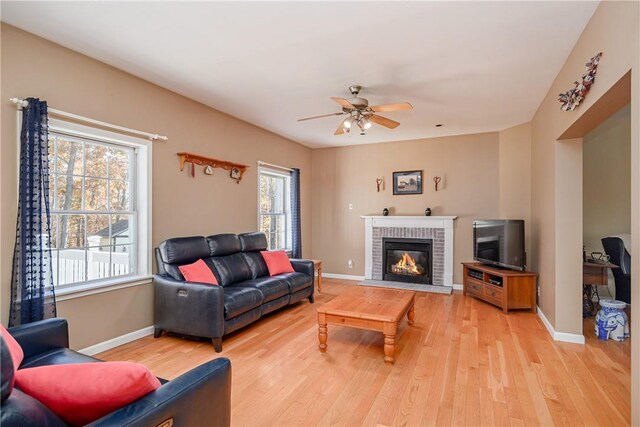 living room with ceiling fan, light hardwood / wood-style floors, a fireplace, and a wealth of natural light