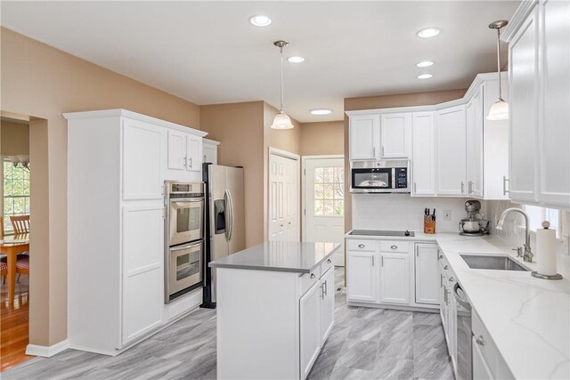 kitchen featuring decorative light fixtures, sink, white cabinetry, and stainless steel appliances