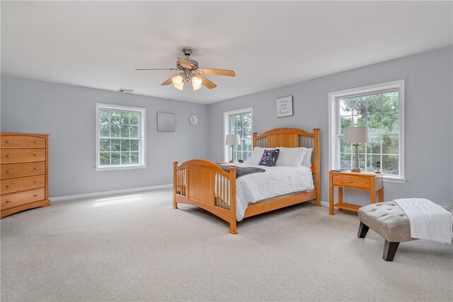 bedroom featuring multiple windows, ceiling fan, and light carpet