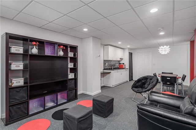 carpeted living room featuring a drop ceiling