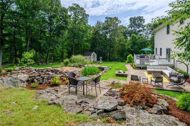 view of yard featuring a wooden deck, a patio, an outdoor hangout area, and a storage shed