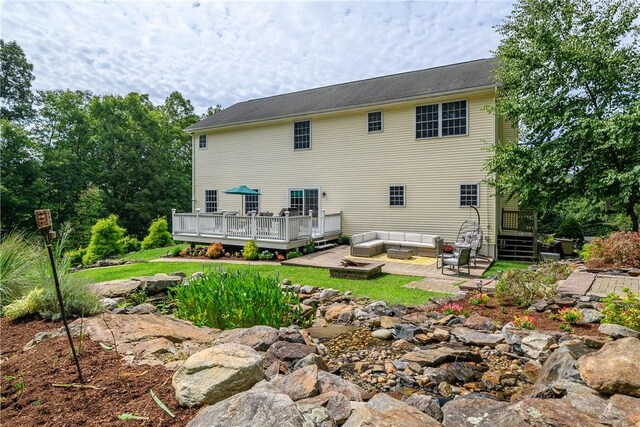 back of property featuring a wooden deck, an outdoor living space, and a patio