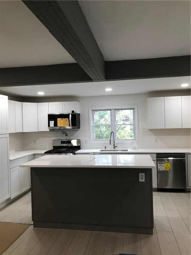 kitchen featuring appliances with stainless steel finishes, sink, beam ceiling, light hardwood / wood-style flooring, and white cabinets