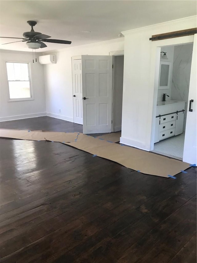 unfurnished room featuring a wall mounted air conditioner, ceiling fan, wood-type flooring, and sink