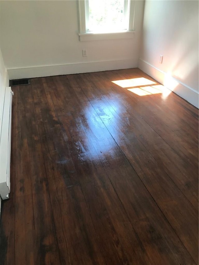 unfurnished room with a baseboard heating unit and dark wood-type flooring