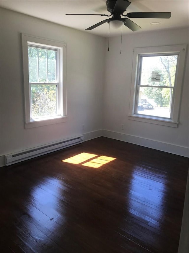 empty room with a wealth of natural light, dark hardwood / wood-style flooring, and a baseboard radiator