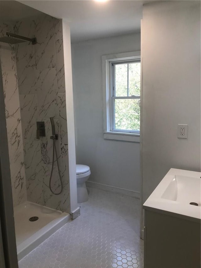 bathroom with a tile shower, tile patterned floors, vanity, and toilet