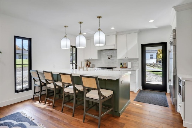 kitchen with pendant lighting, a kitchen breakfast bar, light wood-type flooring, and white cabinetry