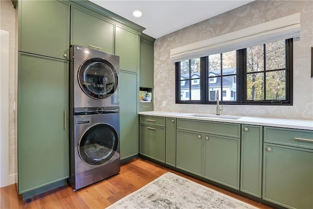 washroom with cabinets, stacked washing maching and dryer, light hardwood / wood-style floors, and sink