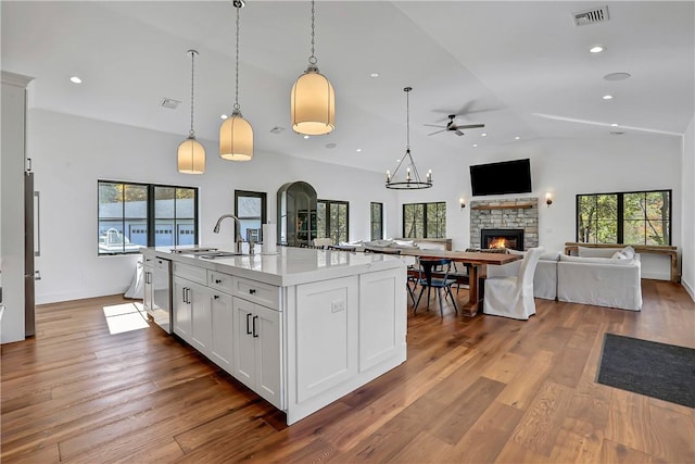 kitchen with a kitchen island with sink, light hardwood / wood-style flooring, ceiling fan, decorative light fixtures, and white cabinetry