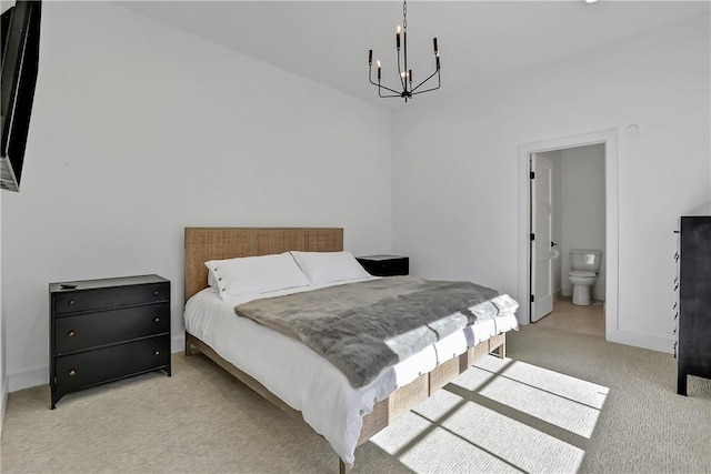 bedroom featuring a chandelier, light colored carpet, and ensuite bath