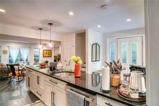 kitchen featuring dishwasher, dark hardwood / wood-style flooring, sink, and dark stone countertops