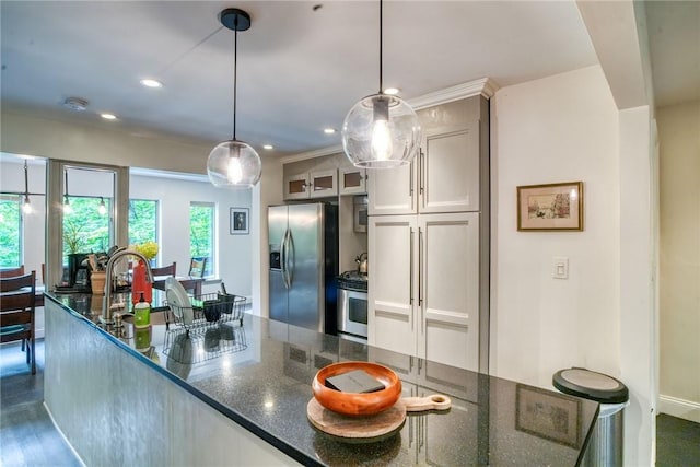 kitchen featuring dark wood-type flooring, hanging light fixtures, dark stone countertops, white cabinets, and appliances with stainless steel finishes