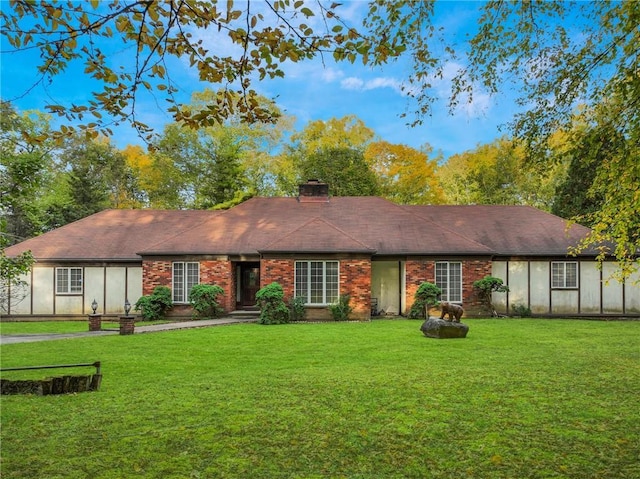 view of front of house with a chimney, a front lawn, and brick siding