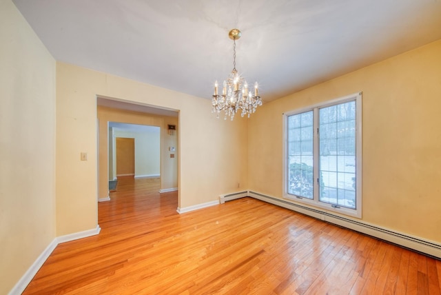 unfurnished room featuring a baseboard heating unit, a chandelier, baseboards, and light wood finished floors