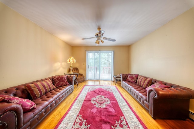 living room with ceiling fan, a baseboard heating unit, and wood finished floors