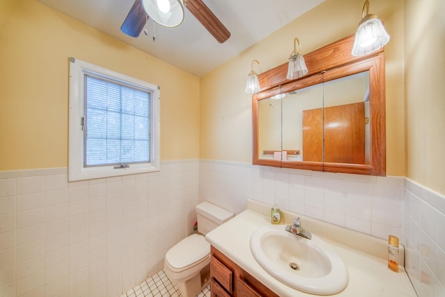 bathroom featuring tile walls, a wainscoted wall, vanity, and toilet