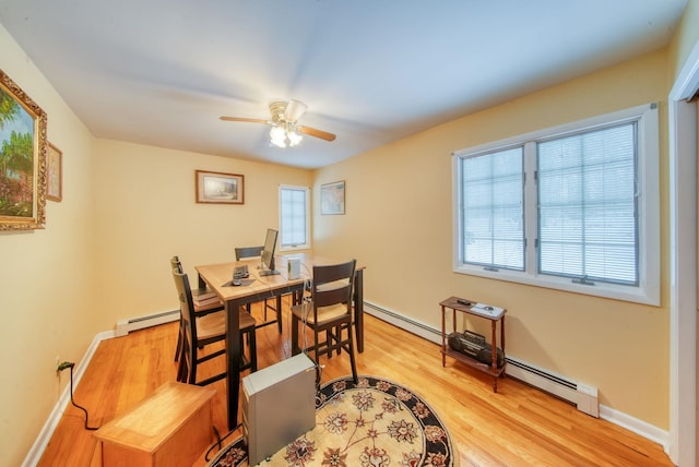 dining space with light wood-style floors, a baseboard radiator, and baseboards