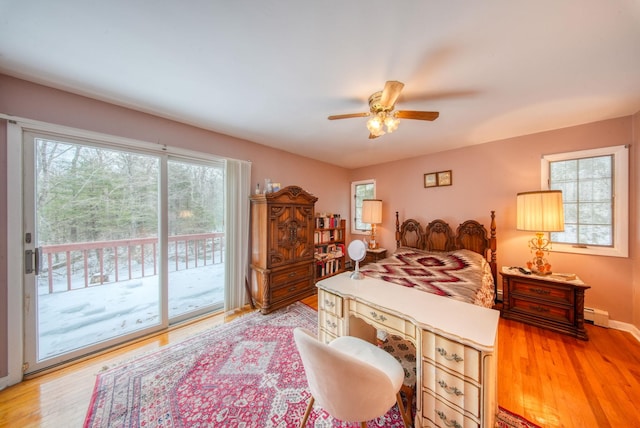 bedroom with access to exterior, a baseboard radiator, multiple windows, and light wood-style floors