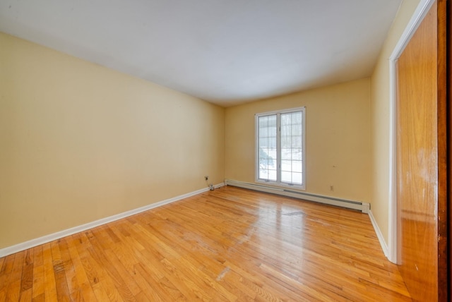 spare room with light wood-style floors, a baseboard radiator, and baseboards