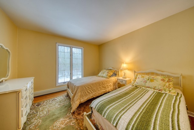 bedroom featuring baseboards, a baseboard heating unit, and wood finished floors