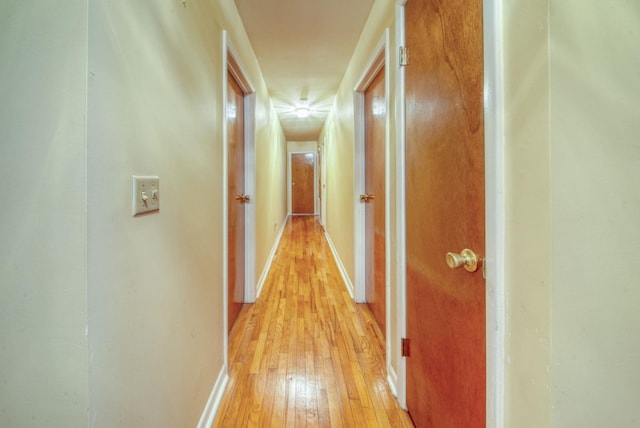 corridor with light wood-type flooring and baseboards