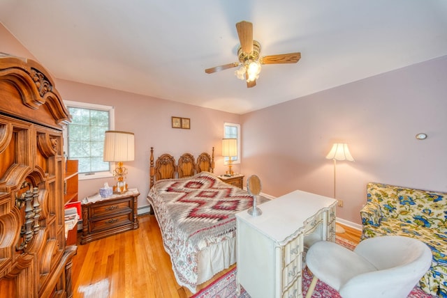 bedroom featuring a baseboard heating unit, baseboards, a ceiling fan, and light wood-style floors