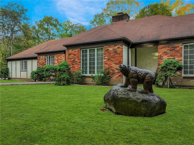 exterior space featuring a yard, roof with shingles, a chimney, and brick siding