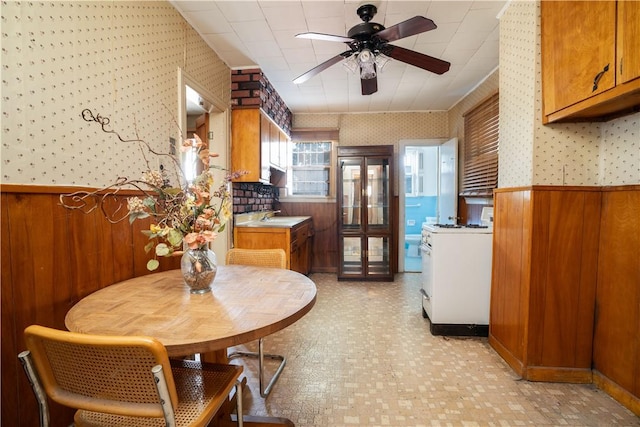 dining room with wooden walls, sink, and ceiling fan