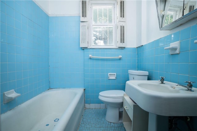 bathroom featuring toilet, tile patterned floors, tile walls, and a bathing tub