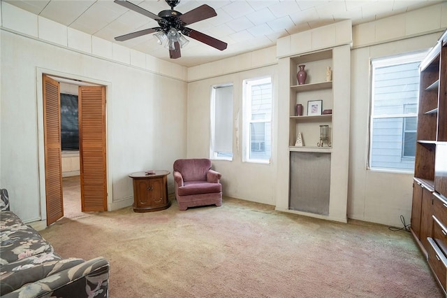 living area featuring light colored carpet and ceiling fan