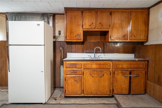 kitchen with wooden walls, sink, and white refrigerator