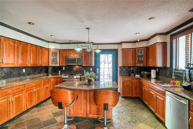 kitchen featuring a center island, sink, stainless steel appliances, pendant lighting, and a breakfast bar area