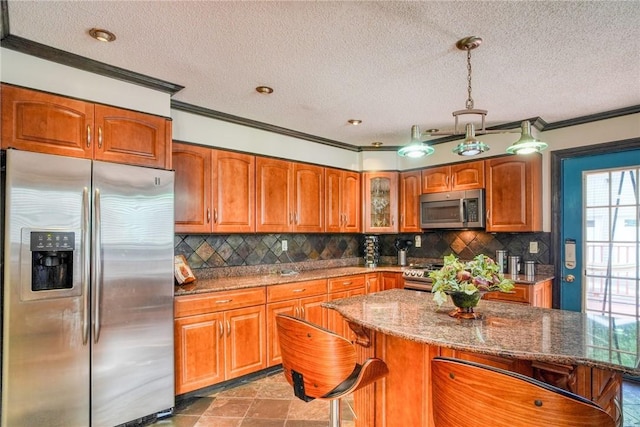 kitchen with pendant lighting, a kitchen breakfast bar, appliances with stainless steel finishes, a kitchen island, and light stone counters