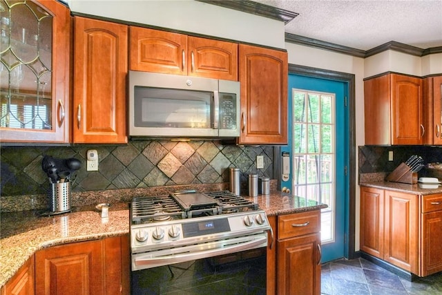 kitchen featuring light stone counters, stainless steel appliances, a textured ceiling, and ornamental molding