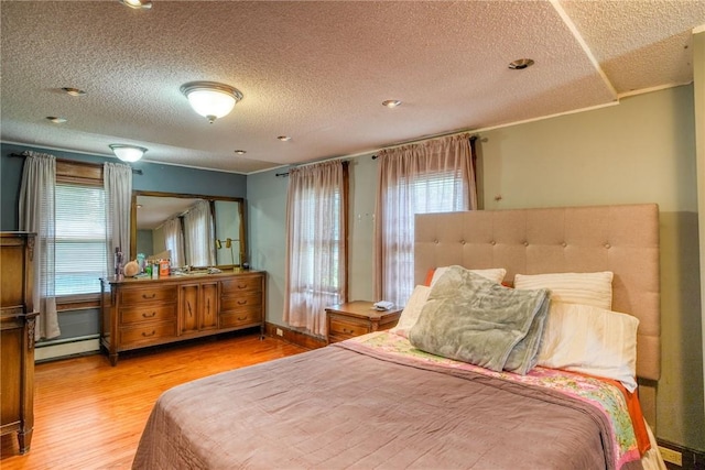 bedroom featuring a textured ceiling, a baseboard radiator, and light hardwood / wood-style flooring