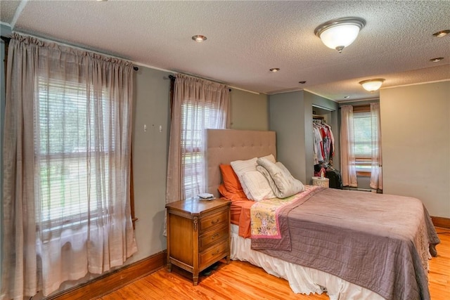 bedroom with a textured ceiling, light wood-type flooring, and a closet